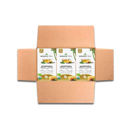 An open cardboard box reveals three cartons of Miracle Tree Organic Moringa Tea, Honey & Vanilla. The vibrant packaging showcases steaming cups and lush moringa leaves, proudly displaying organic and non-GMO certifications. Enjoy this caffeine-free superfood infusion packed with benefits.