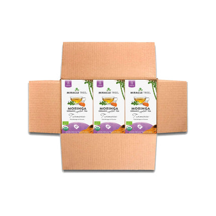 Open cardboard box with three Miracle Tree Organic Moringa Tea, Turmeric boxes, each featuring Turmeric and a teacup image. This superfood blend promises wellness in every sip.