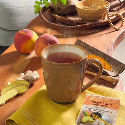 Tea cup with ginger peach turmeric mix on a wooden table with peaches and spices.